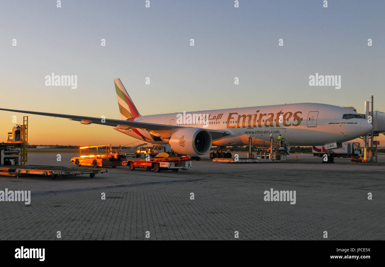 Die untergehende Sonne erhellt ein Emirates Air Boeing 777 stationär an einem Flughafen Stockfoto