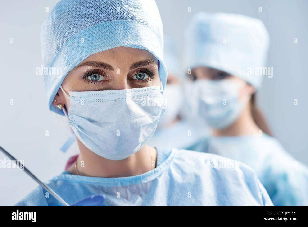 Close-up Portrait von jungen weiblichen Chirurgen Arzt im Betrieb Theater. Gruppe von Chirurgen bei der Arbeit. Gesundheitswesen, medizinische Ausbildung, Notfall medizinische ser Stockfoto