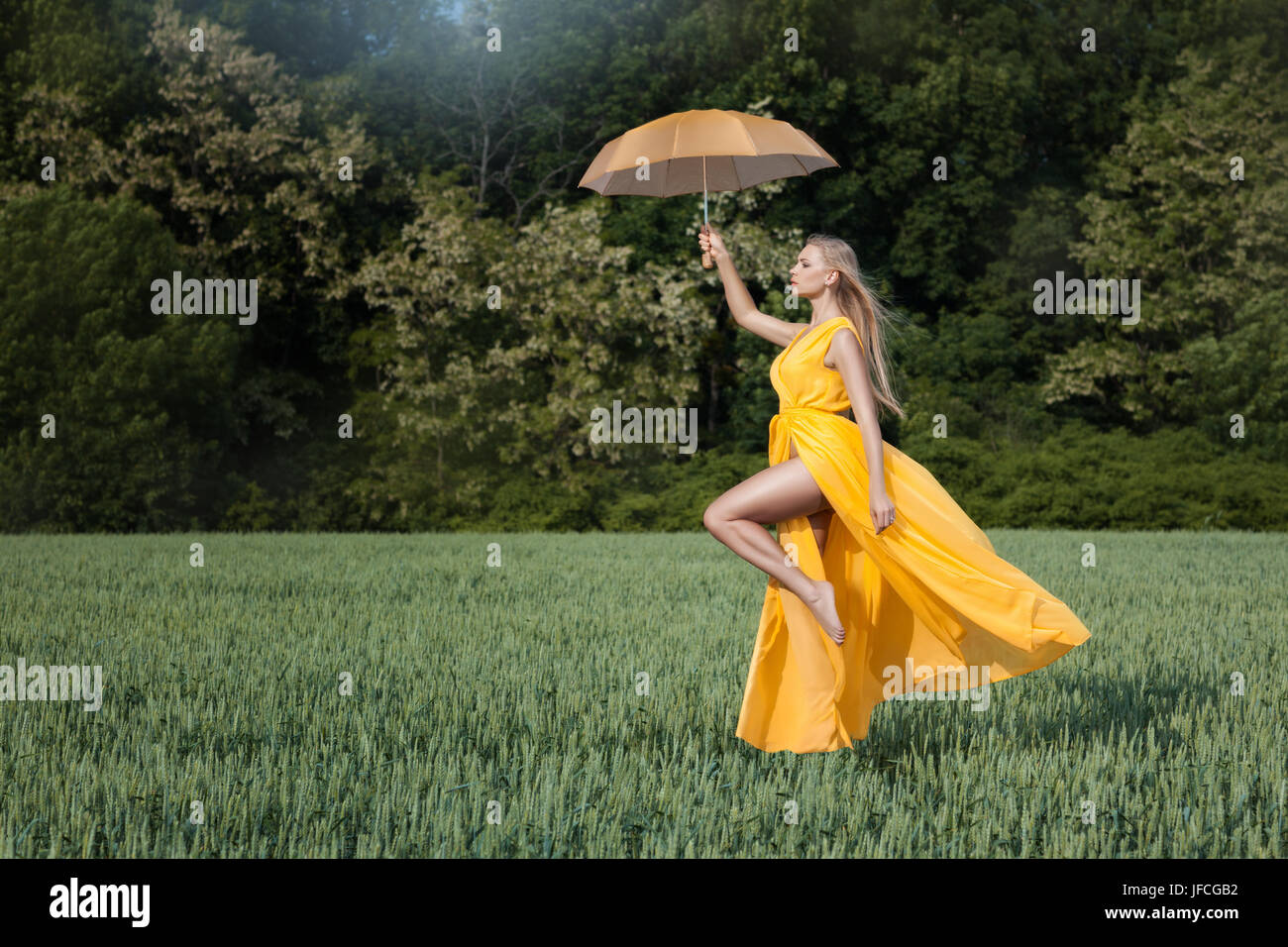 Mädchen fliegt über das Feld. In ihren Händen hält sie einen Regenschirm. Stockfoto