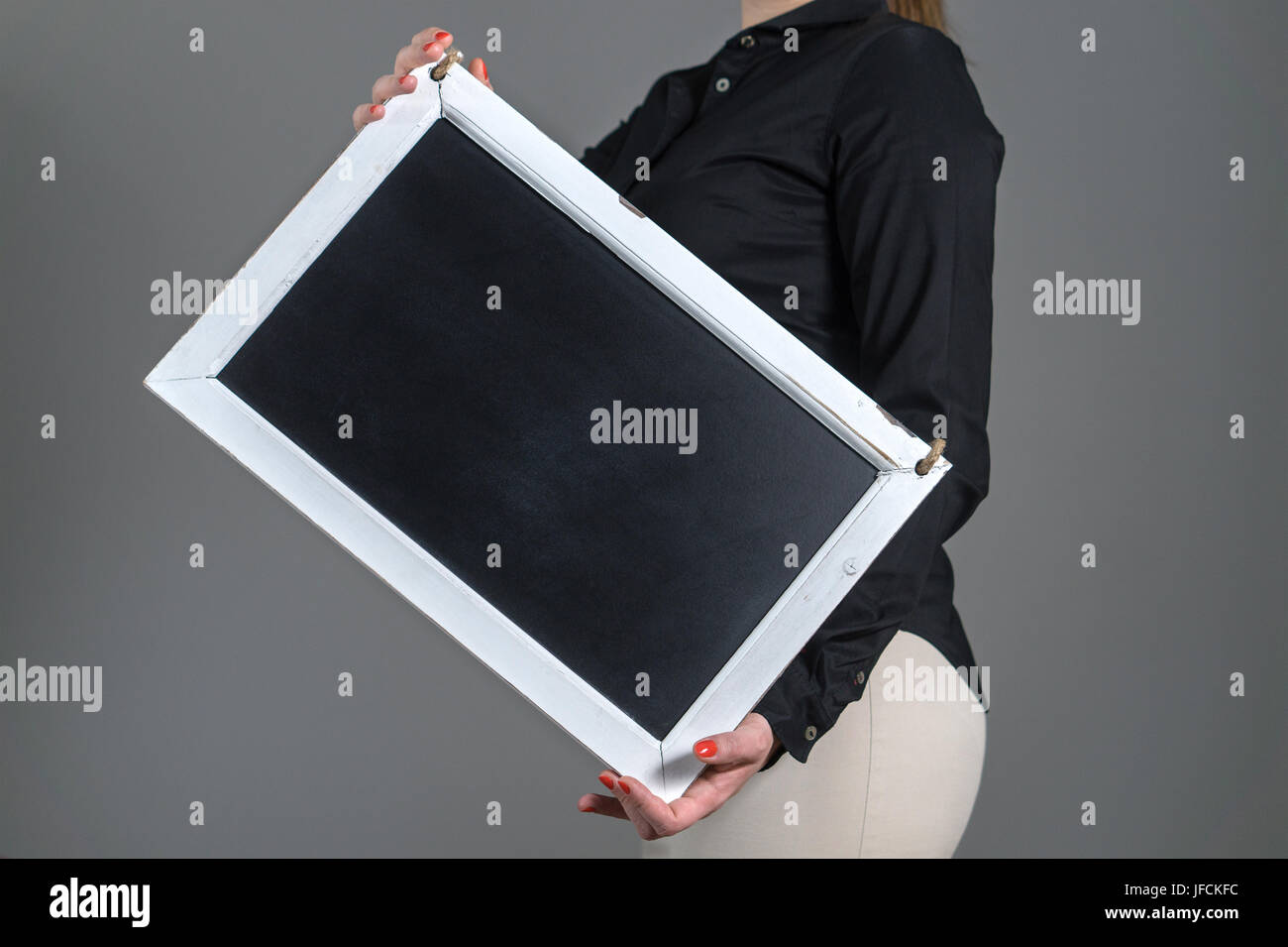 Frau mit gekippten Tafel auf einen dunkelgrauen Hintergrund. Leer leer Freiexemplar Platz für Text, Menü oder Specials. Kellnerin in einem Restaurant. Stockfoto