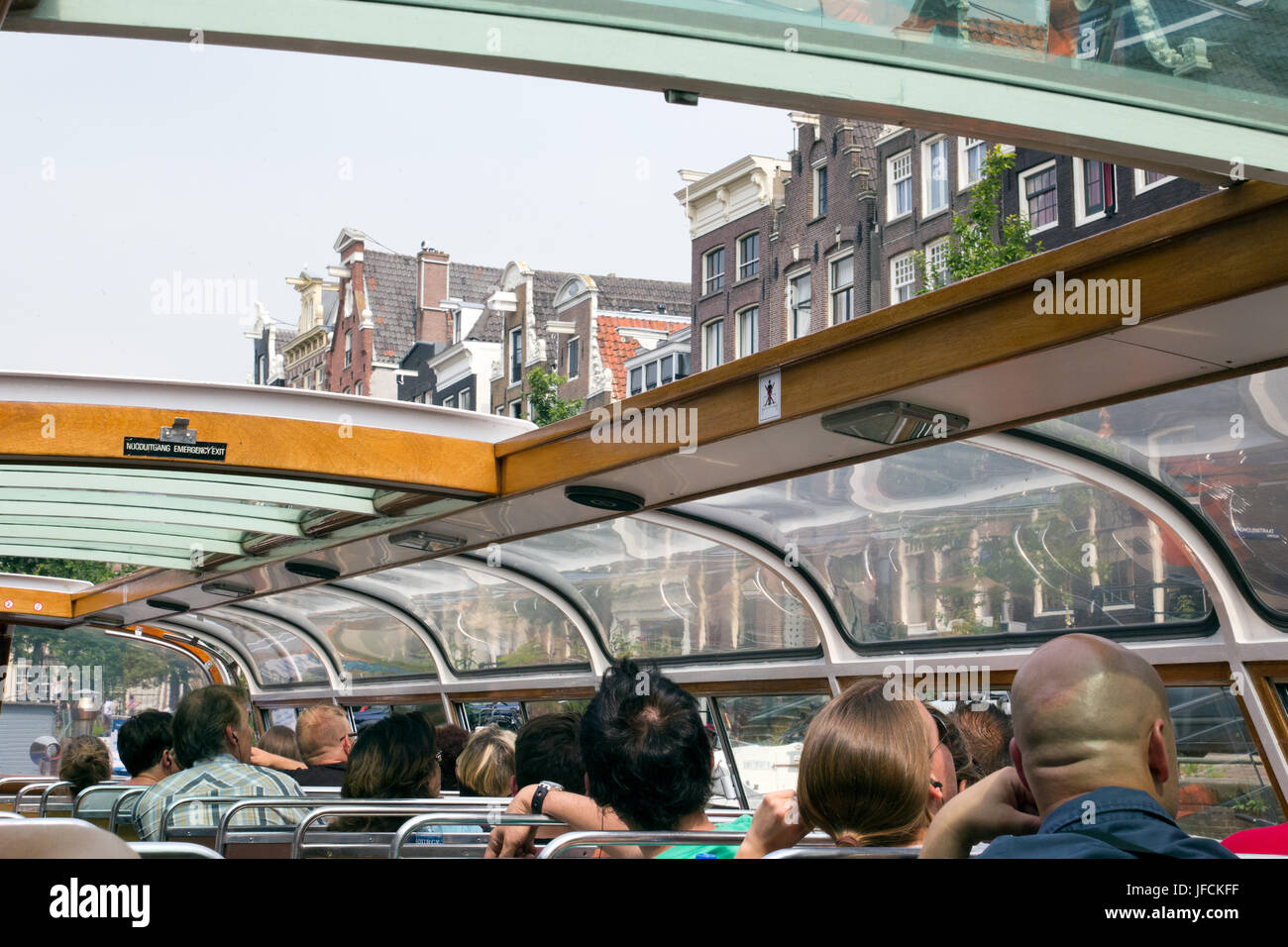 AMSTERDAM, NIEDERLANDE - 27. JULI 2012. Touristen, die Amsterdam von einem Kanalboot am 27. Juli 2012 beobachten. Amsterdam ist die am meisten wässrigen Stadt im w Stockfoto