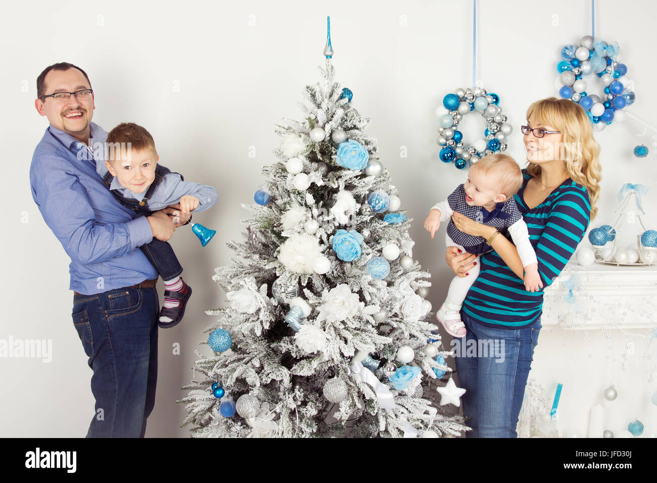 Glückliche Familie von vier Personen (Mutter, Vater, Sohn, Tochter) schmücken Weihnachtsbaum Stockfoto