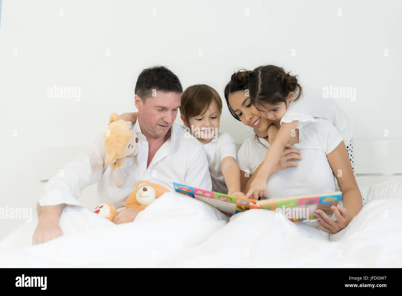 Asiatischen Brüder und asiatische Tochter Lesebuch zusammen im Bett im Schlafzimmer mit Vater und Mutter. Glückliche Familien-Konzept. Stockfoto