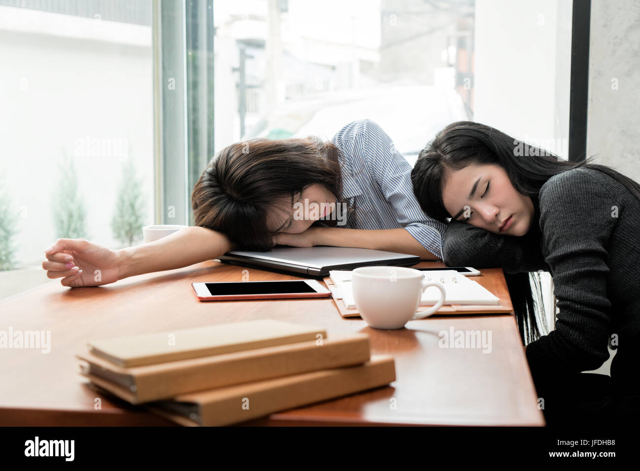 Überarbeitet und müde.  Zwei asiatische Geschäftsfrau schlafen über einen Laptop in einem Schreibtisch bei der Arbeit im Büro. Stockfoto