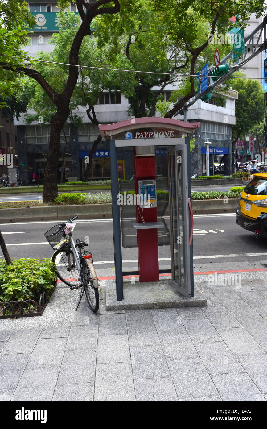 Ein Fahrrad neben einer öffentlichen Telefonzelle auf dem Bordstein in Taipei, Taiwan entlang der Straße geparkt. Stockfoto