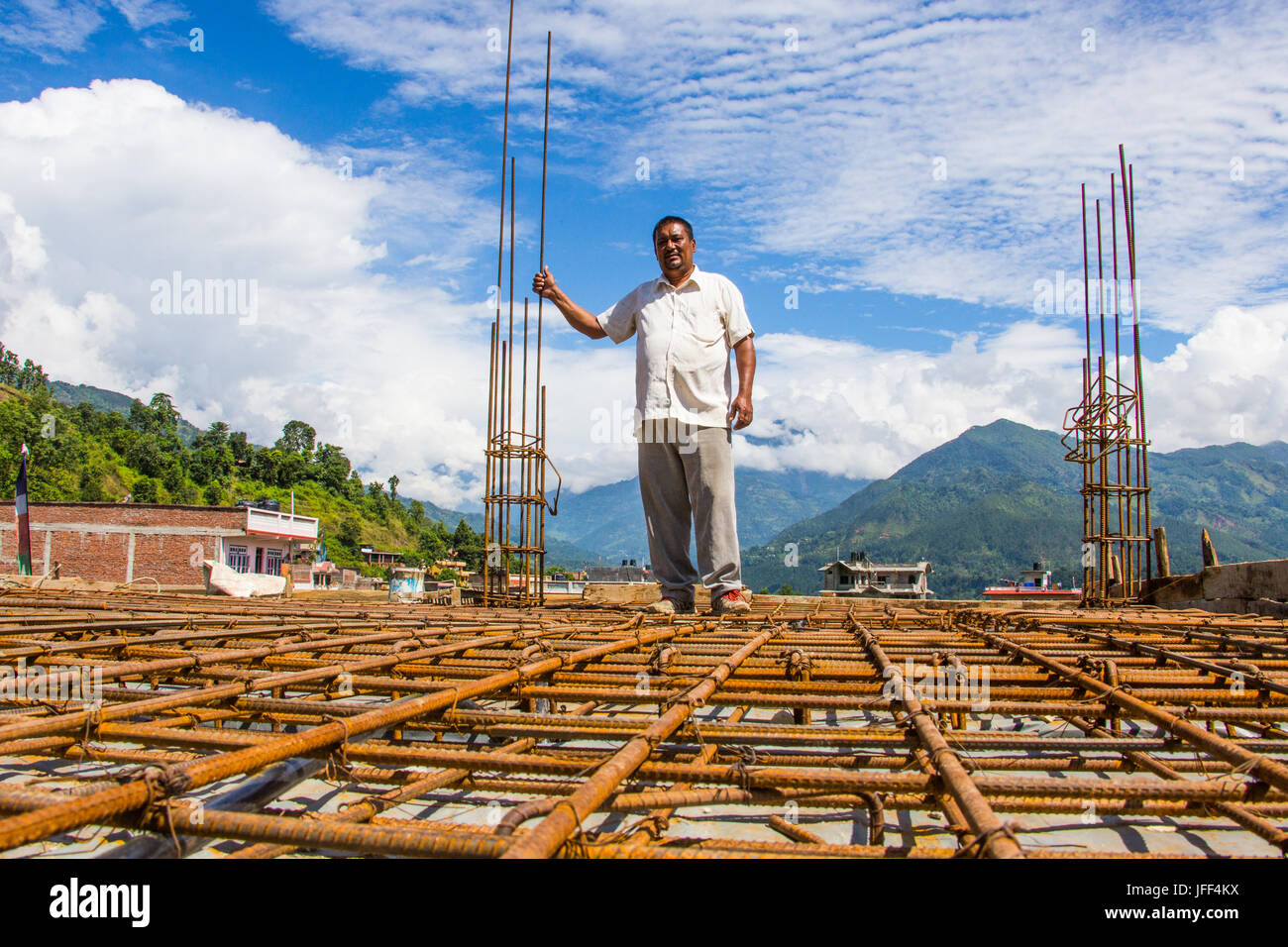 Nepali Mason stehen auf einer Schicht von Bewehrung des Hauses, die er baut, Nuwakot Bezirk, Nepal Stockfoto