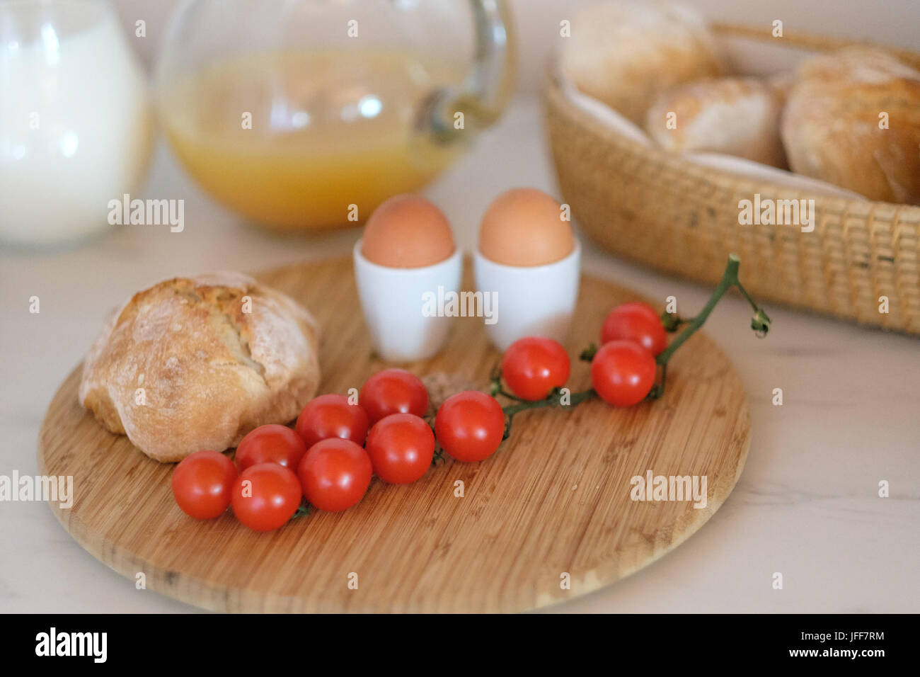 Gesundes Frühstück mit gekochten Eiern, Brot, Tomaten, Milch und Orangensaft Stockfoto