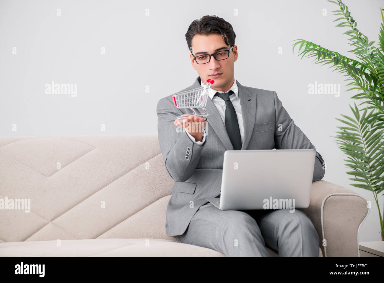 Geschäftsmann mit Laptop und Warenkorb Stockfoto