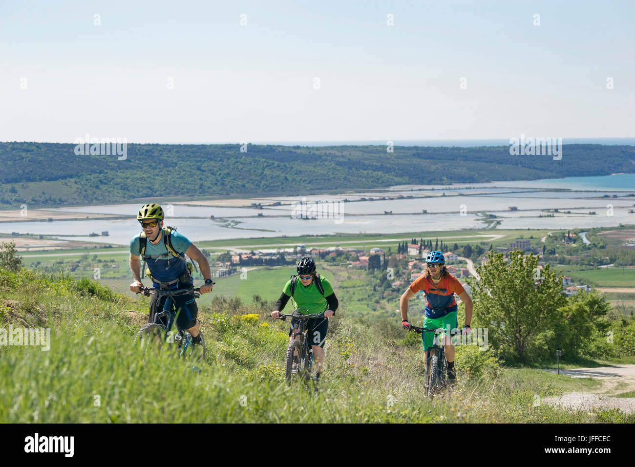 Biker durchläuft Gras- und Häuser und Seen im Hintergrund Stockfoto