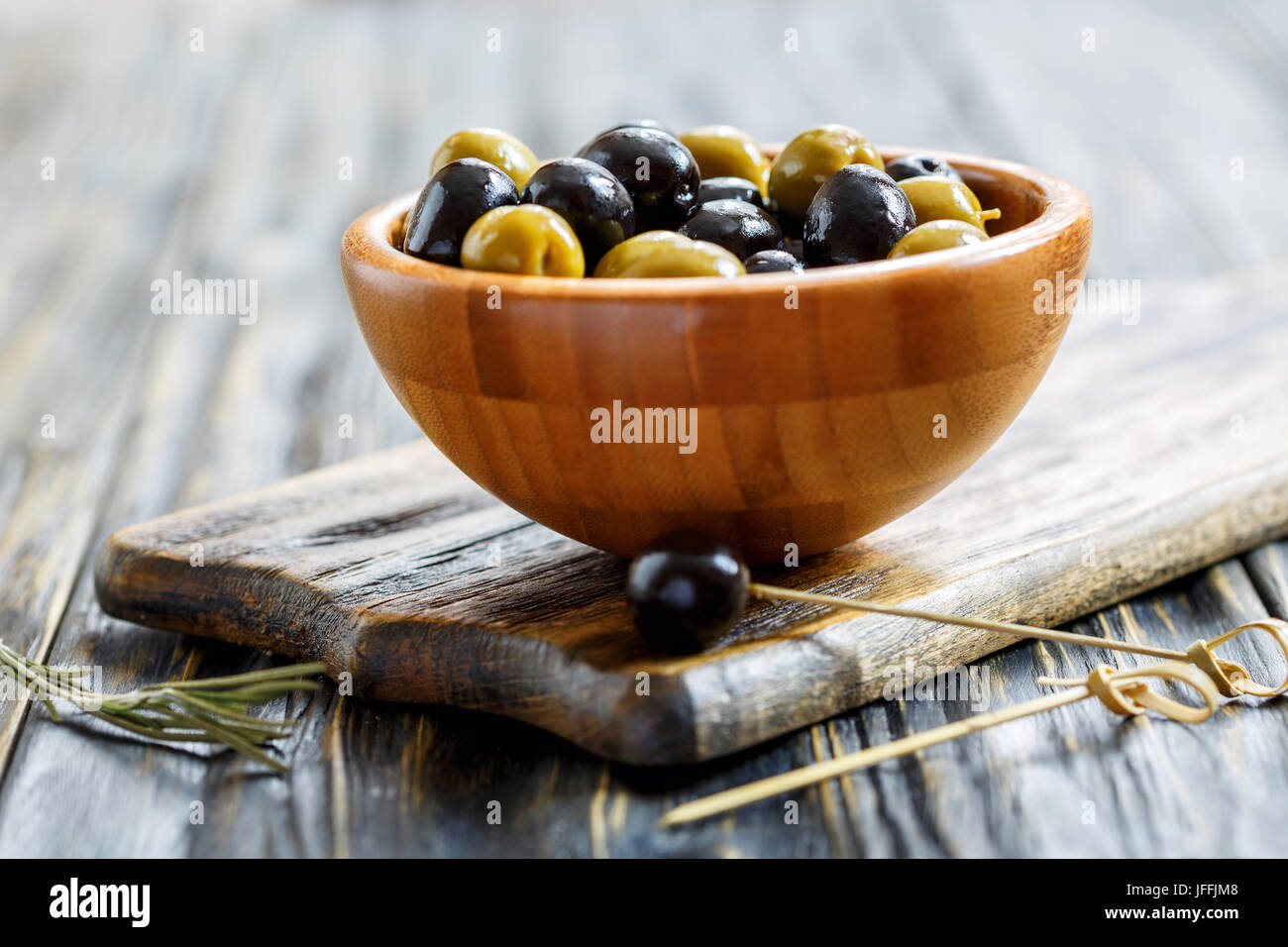 Schwarze und Grüne Oliven in eine hölzerne Schüssel. Stockfoto