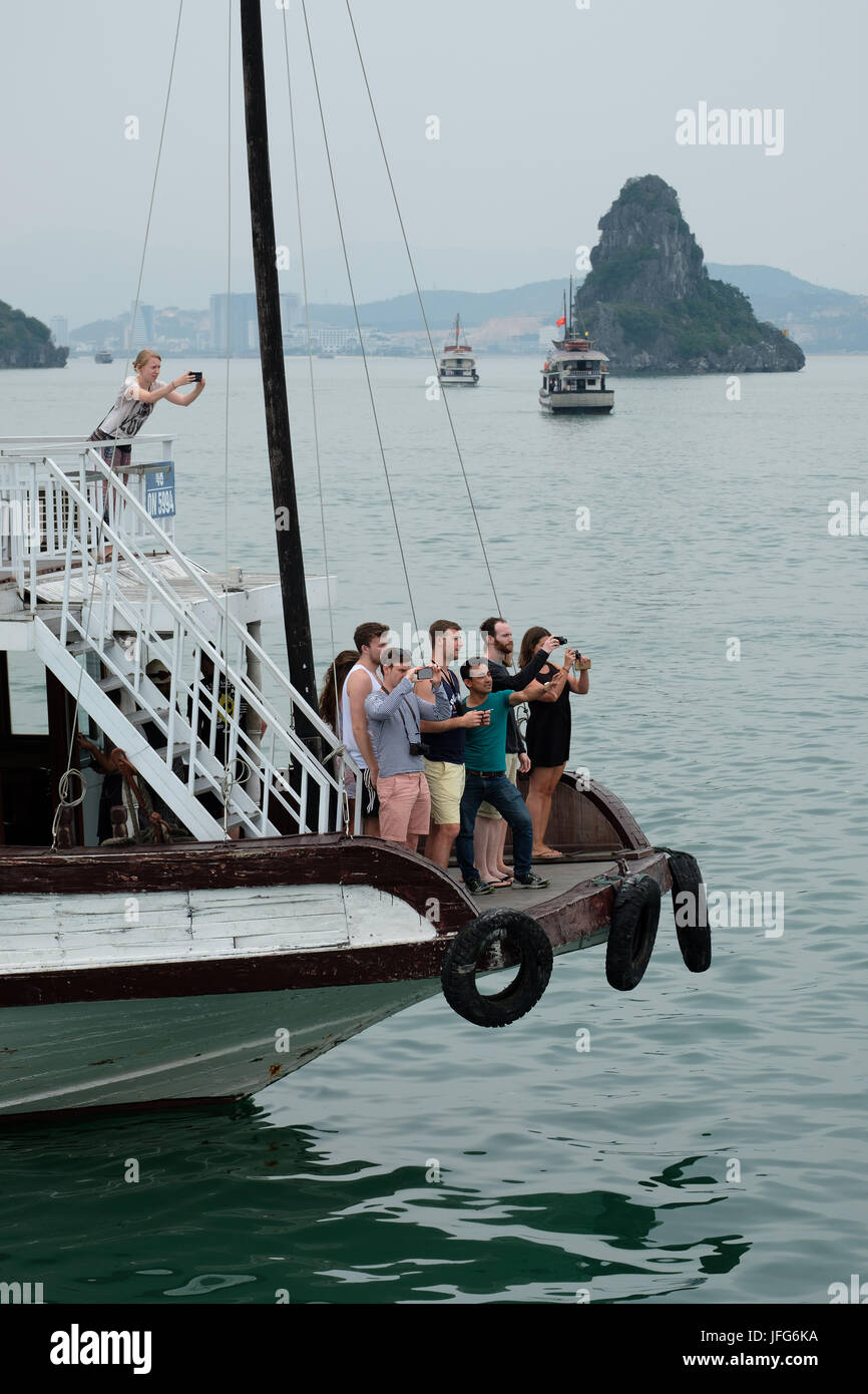 Touristen fotografieren während der Fahrt auf einem Boot in der Halong Bay, Vietnam, Asien Stockfoto
