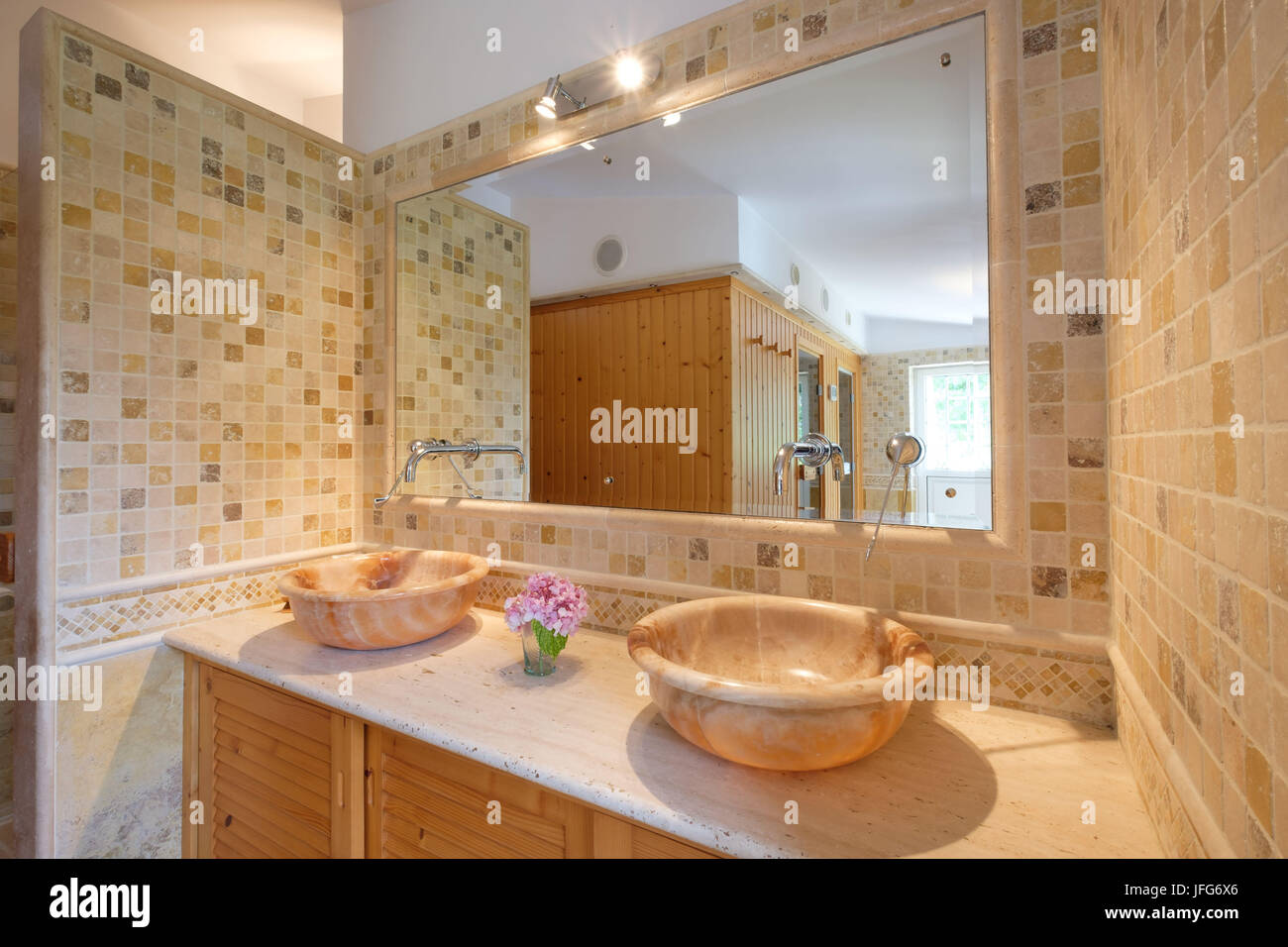 Badezimmer mit zwei Waschbecken, hellgelbe Fliesen und großer Spiegel Stockfoto