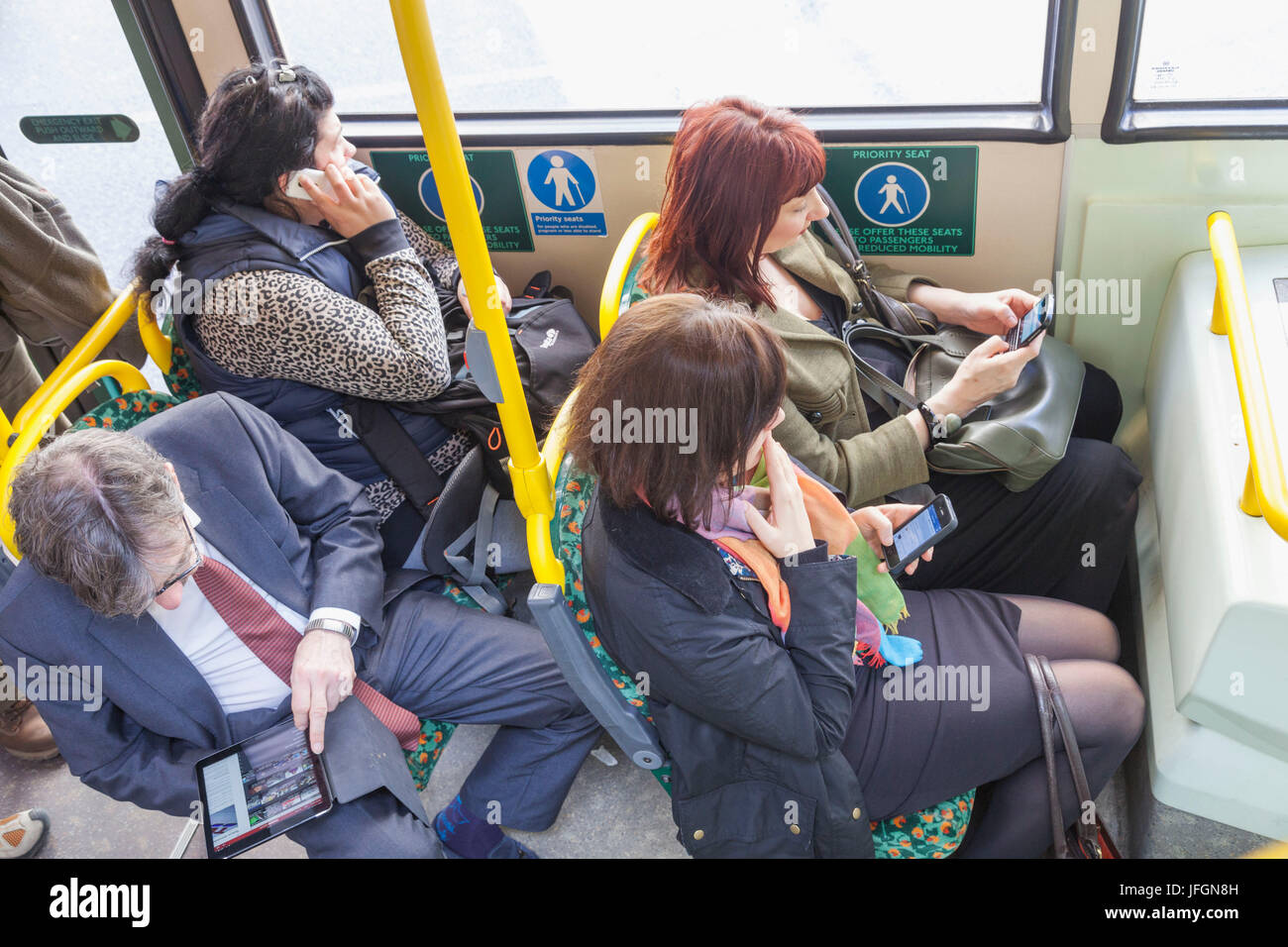 England, London, City of London, Bus-Passagiere, die mit elektronischen Geräten Stockfoto