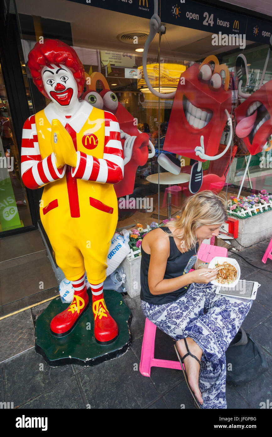 Thailand, Bangkok, Khaosan Road, weibliche westliche Touristen Essen Pad Thai vor McDonalds Stockfoto