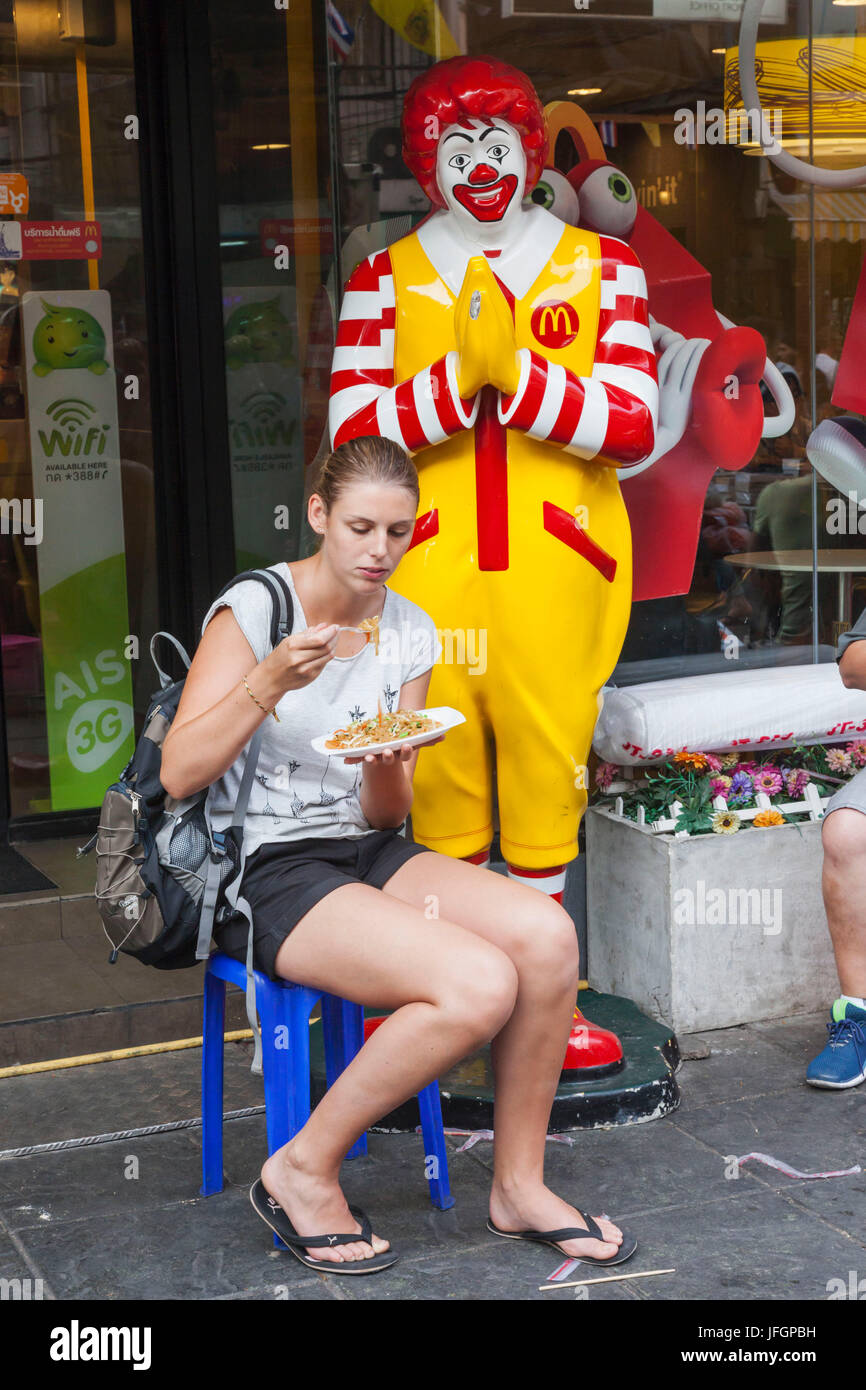 Thailand, Bangkok, Khaosan Road, weibliche westliche Touristen Essen Pad Thai vor McDonalds Stockfoto