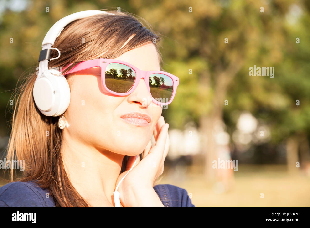 Frau durch Musik hören im park Stockfoto