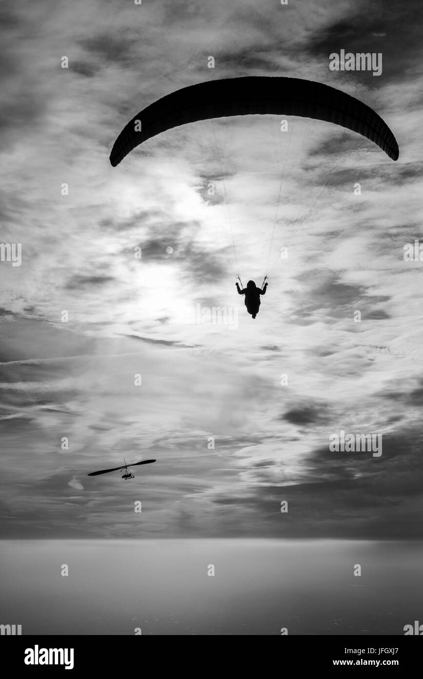 Gleitschirm und Delta im stimmungsvollen Himmel über Inversionsschicht, Luftbild, Sonnenbaden, Bassano, Monte Grappa, Veneto, Italien Stockfoto