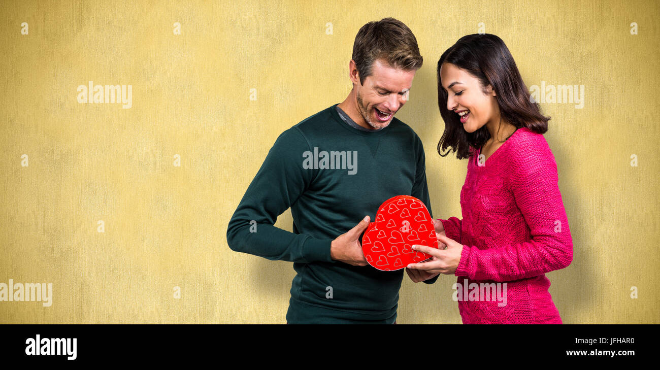 Zusammengesetztes Bild von glücklichen jungen Paar mit Herz Form Geschenk Stockfoto