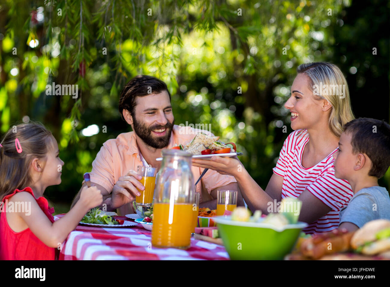Mutter mit Salat und Familie am Tisch sitzen Stockfoto