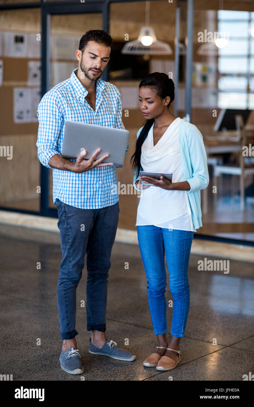 Junger Mann und Frau diskutieren mit digitalen Tablet und Notebook Stockfoto