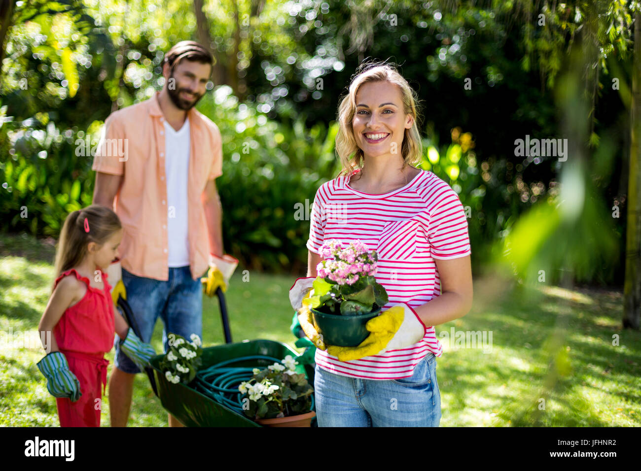 Frau mit Blumentopf mit Familie am Hof Stockfoto