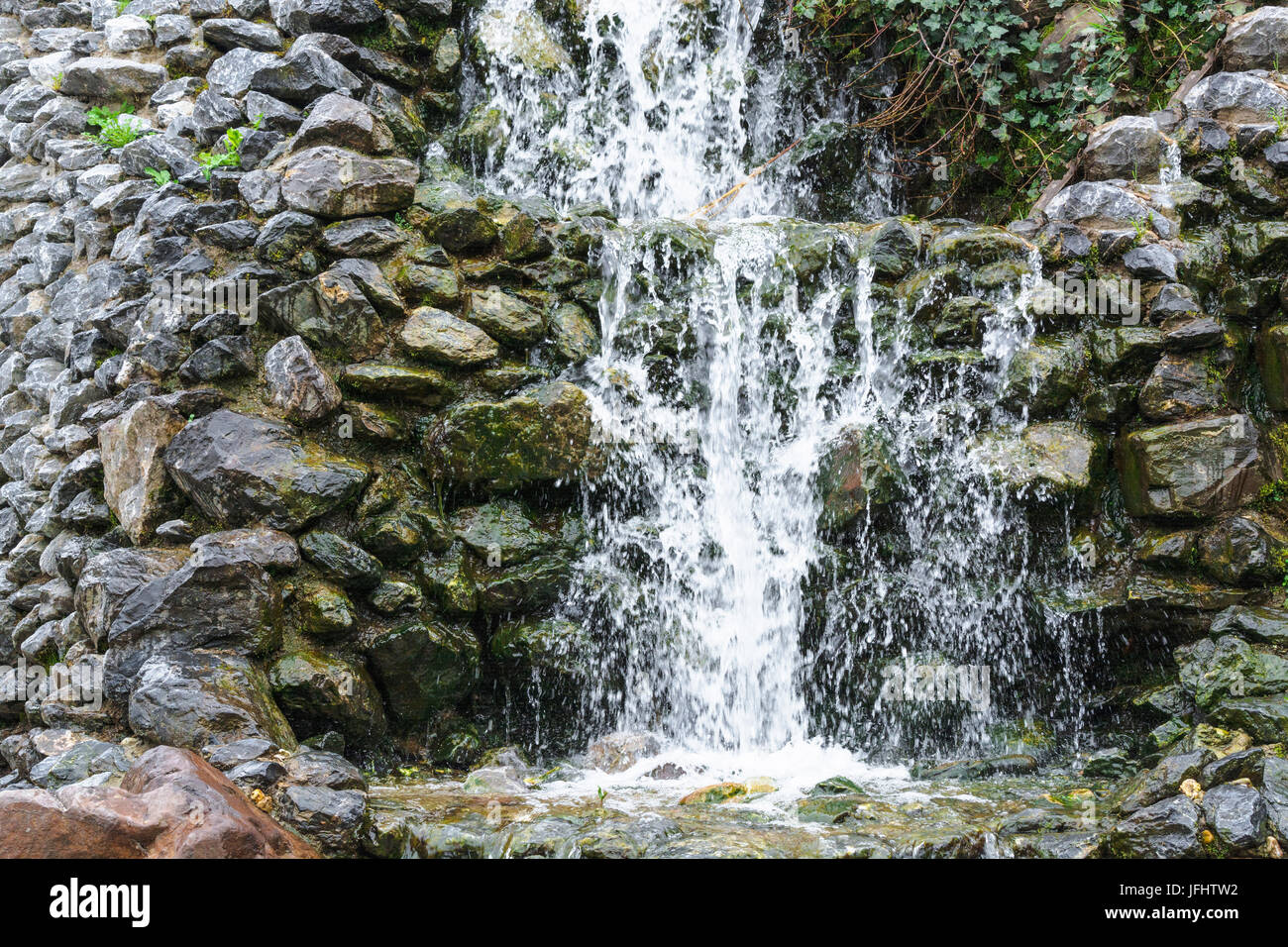 Kleiner Wasserfall, Kaskade über Bemoosten Felsbrocken fließt Stockfoto