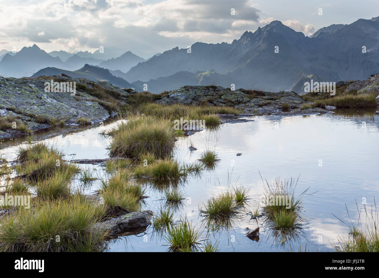 Bergsee, Rasen, Himmel, Wolken, Gipfel Stockfoto