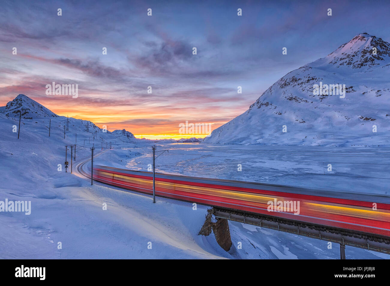 Der Bernina Express führt am Ufer des Sees Bianco komplett eingefroren, bevor die Sonne aufgeht, Kanton Graubünden, Engadin, Schweiz, Europa Stockfoto