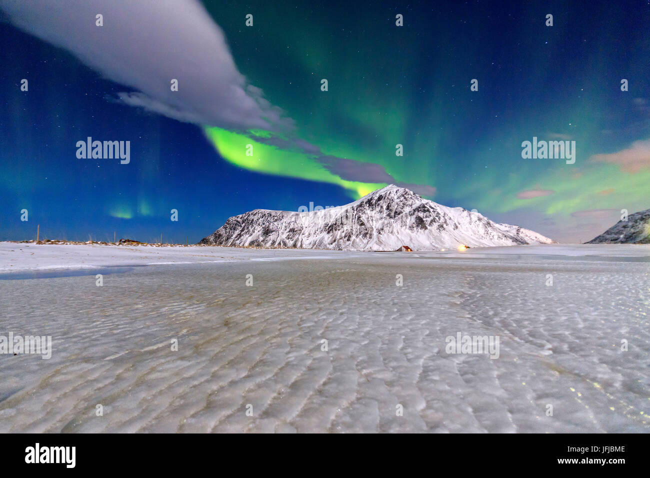 Nordlichter erhellen den Himmel und den schneebedeckten Gipfeln, Flakstad, Lofoten Inseln Norwegen Nordeuropa Stockfoto