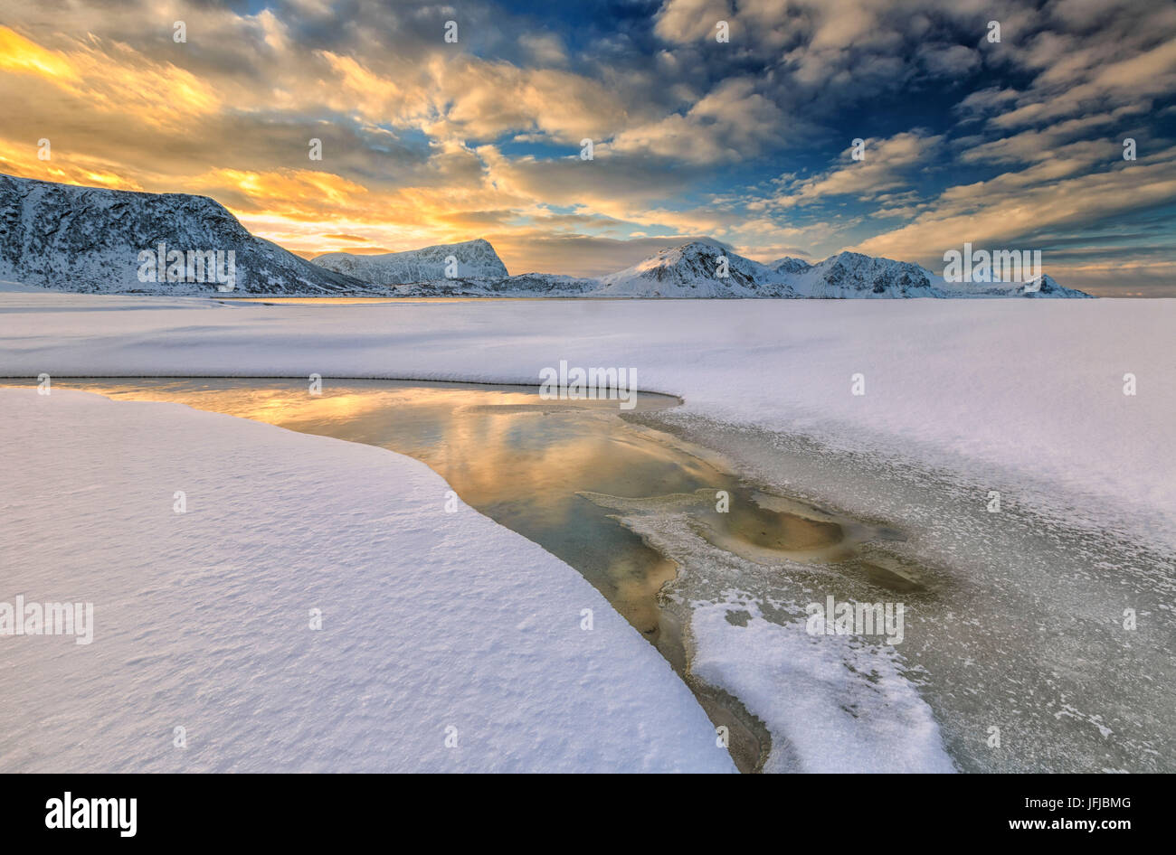 Die goldene Sonnenaufgang spiegelt sich in einem Pool an das klare Meer, wo der Schnee ist fast geschmolzen, Haukland Lofoten Inseln Norwegen Europa Stockfoto