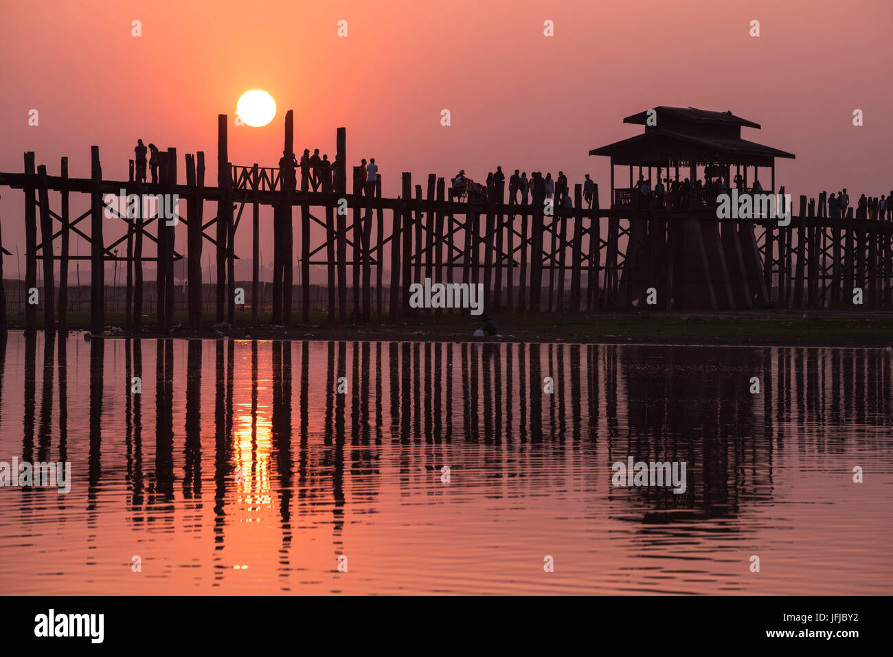 Amarapura, Mandalay Region, Myanmar, Silhouetted Menschen gehen auf die U Bein Brücke bei Sonnenuntergang, Stockfoto