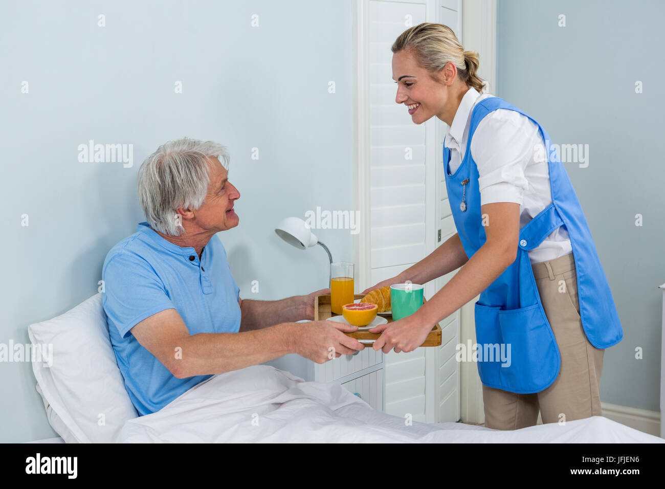 Krankenschwester bietet Frühstück, entspannen Sie sich auf Bett senior woman Stockfoto