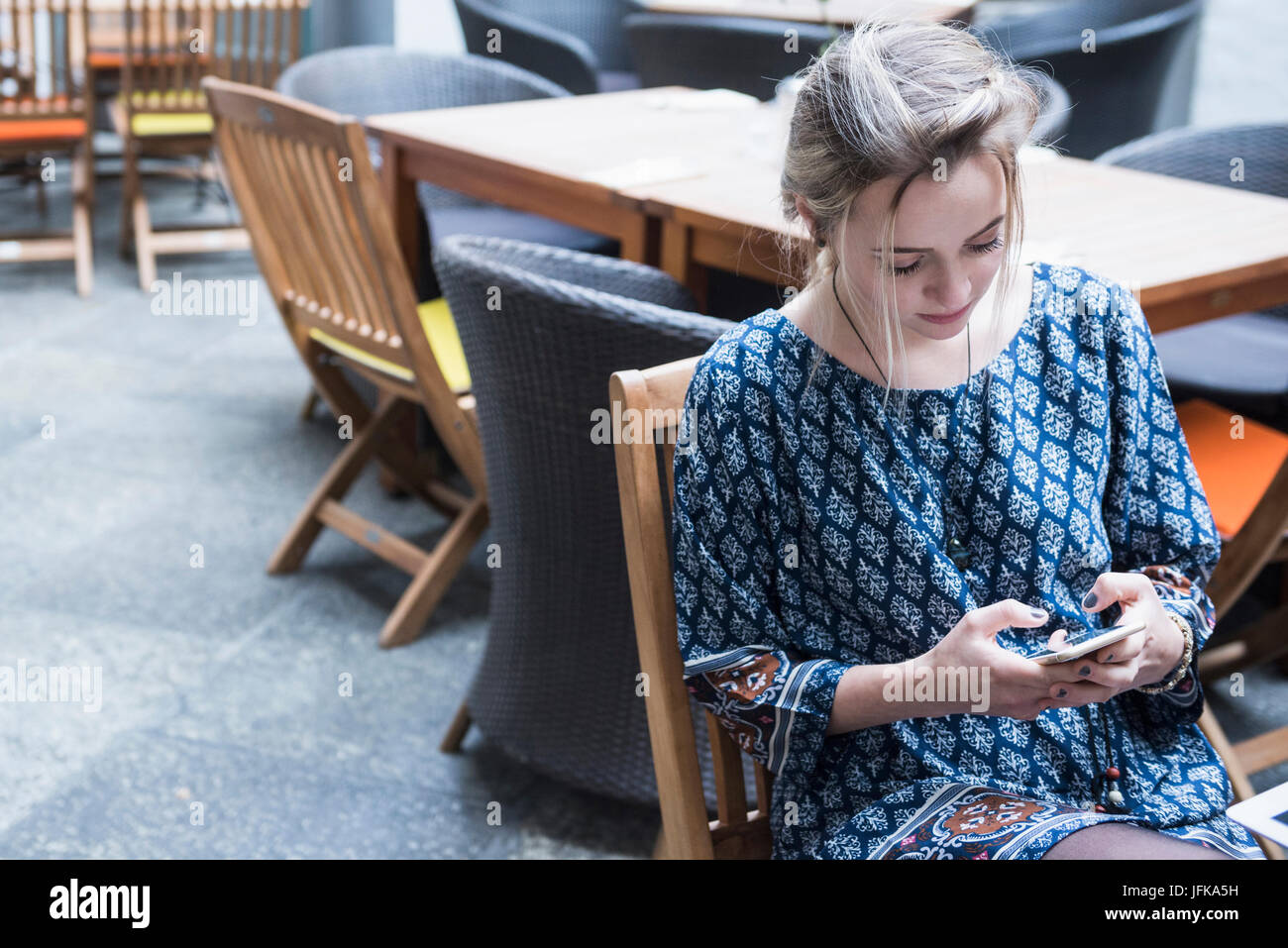 Junge Frau von SMS-Nachrichten beim Sitzen im restaurant Stockfoto