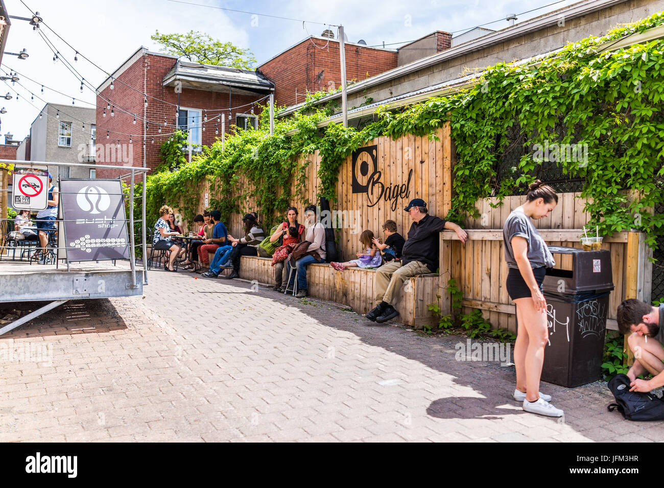 Montreal, Kanada - 28. Mai 2017: Leute sitzen außerhalb Restaurants in der Nähe von Jean-Talon Landwirte mit Bagel und Sushi Zeichen während der sonnigen Tag am Stockfoto