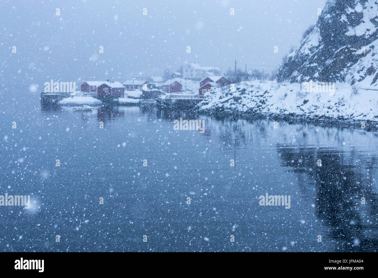 Schneefall in einer kleinen Bucht von Nusfjord Fischerdorf, Lofoten Inseln, Norwegen Stockfoto