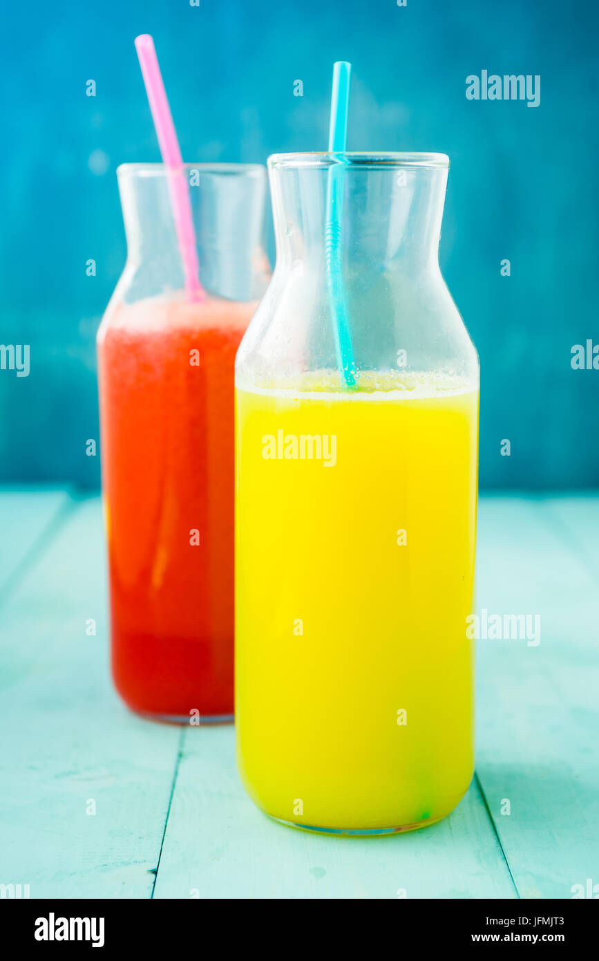 Flasche frisch gepressten Orangensaft und Roter Beete, frisch gepressten Saft im Glas auf blauem Hintergrund. Gesundes rohes Gemüse und Obst trinken für Entgiftung auf eine Stockfoto