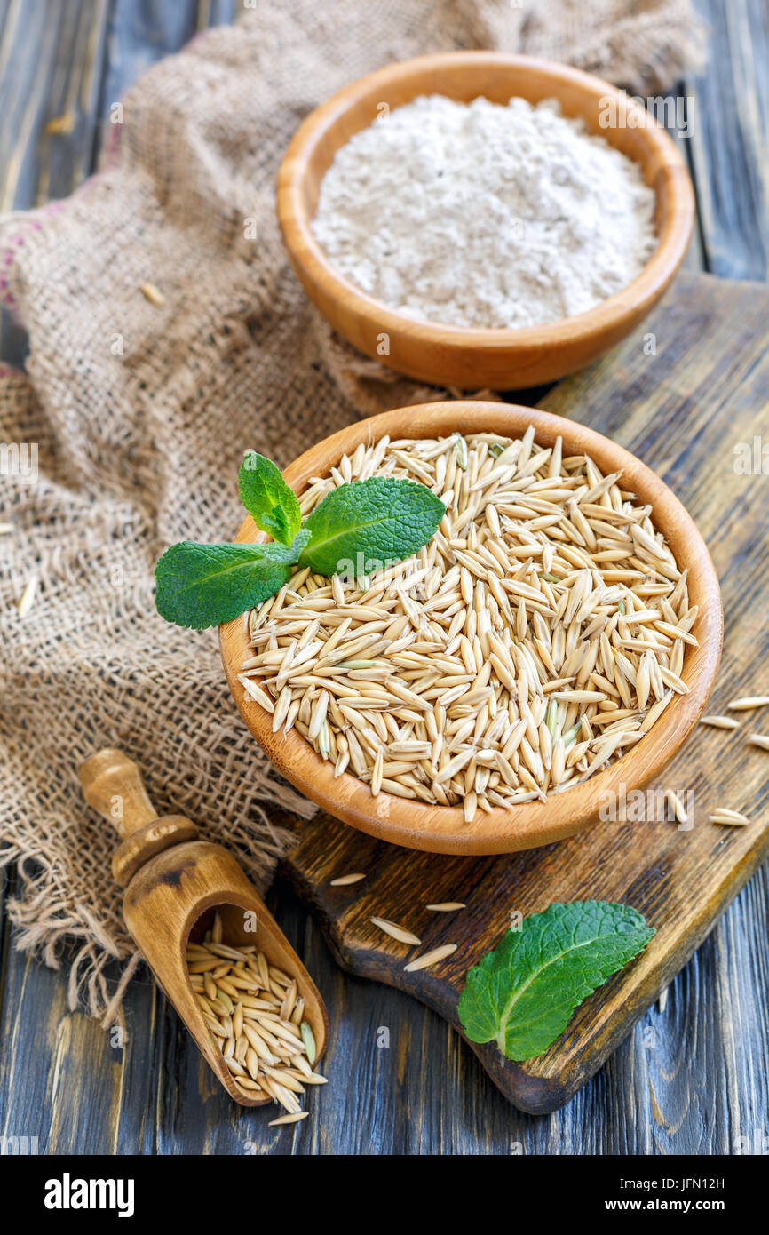 Haferflocken und Hafer in hölzernen Schüsseln. Stockfoto