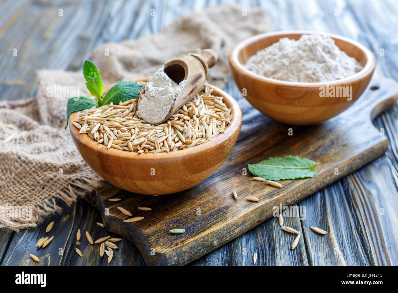 Haferflocken und Hafer in hölzernen Schüsseln. Stockfoto