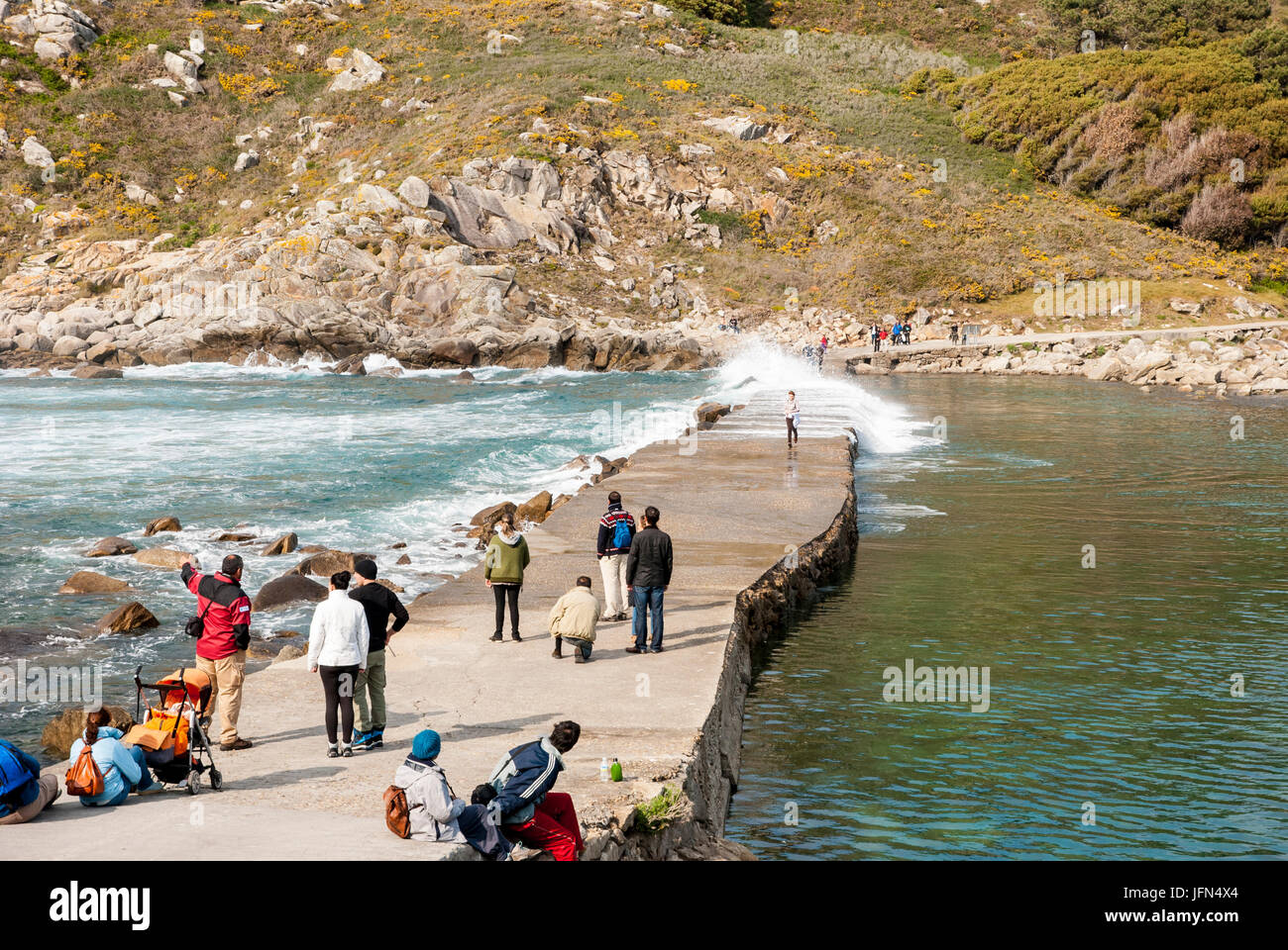 VIGO, Spanien - 7. APRIL: Menschen warten, um den Pfad auf das Meer zu überqueren, ohne nass von der Welle. Aufgenommen am Cies Inseln Naturpark, Galizien, Spanien Stockfoto