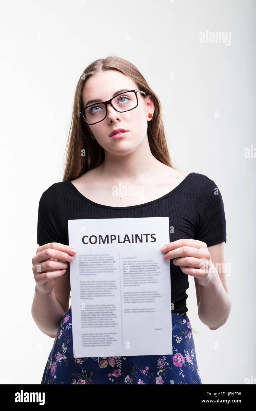 Ernste junge Frau mit Brille mit einer langen Liste von Beschwerden in ihr Hände auf der ständigen Suche sichern rollenden Augen in einem konzeptionellen Bild über eine Stockfoto