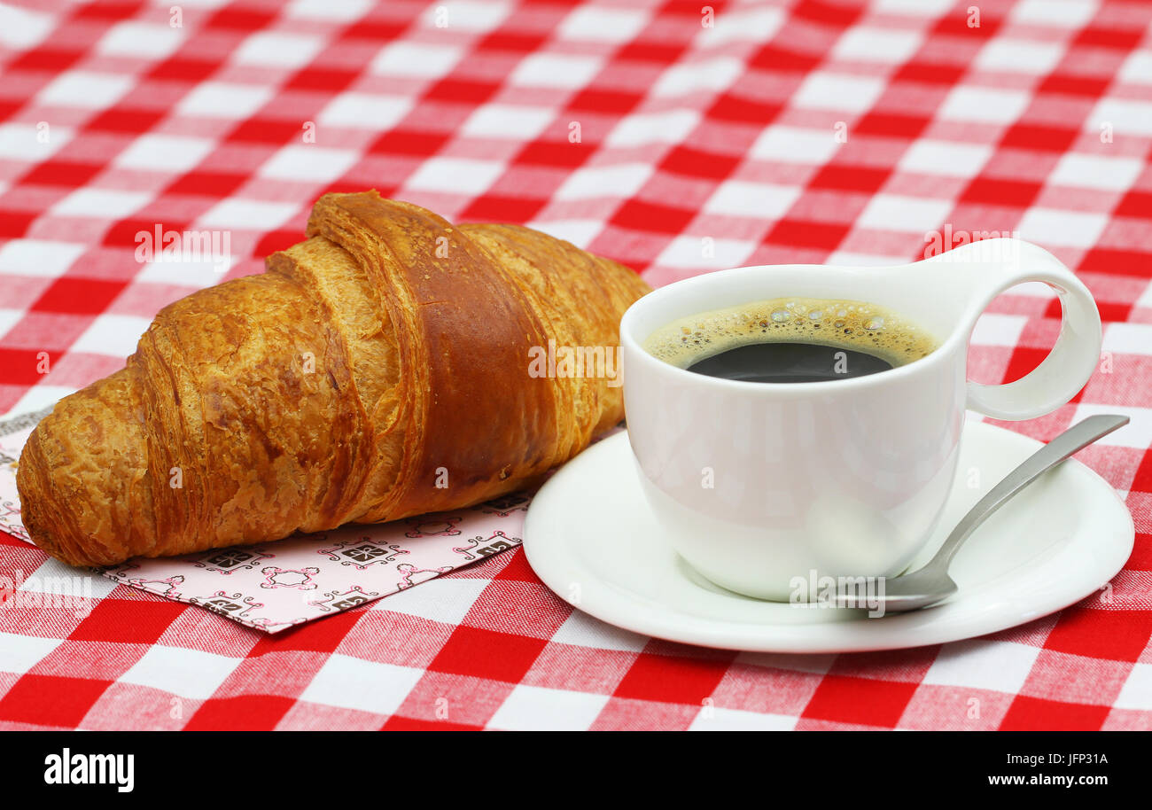 Frische Croissant mit schwarzen Kaffee auf kariertem Stoff Stockfoto
