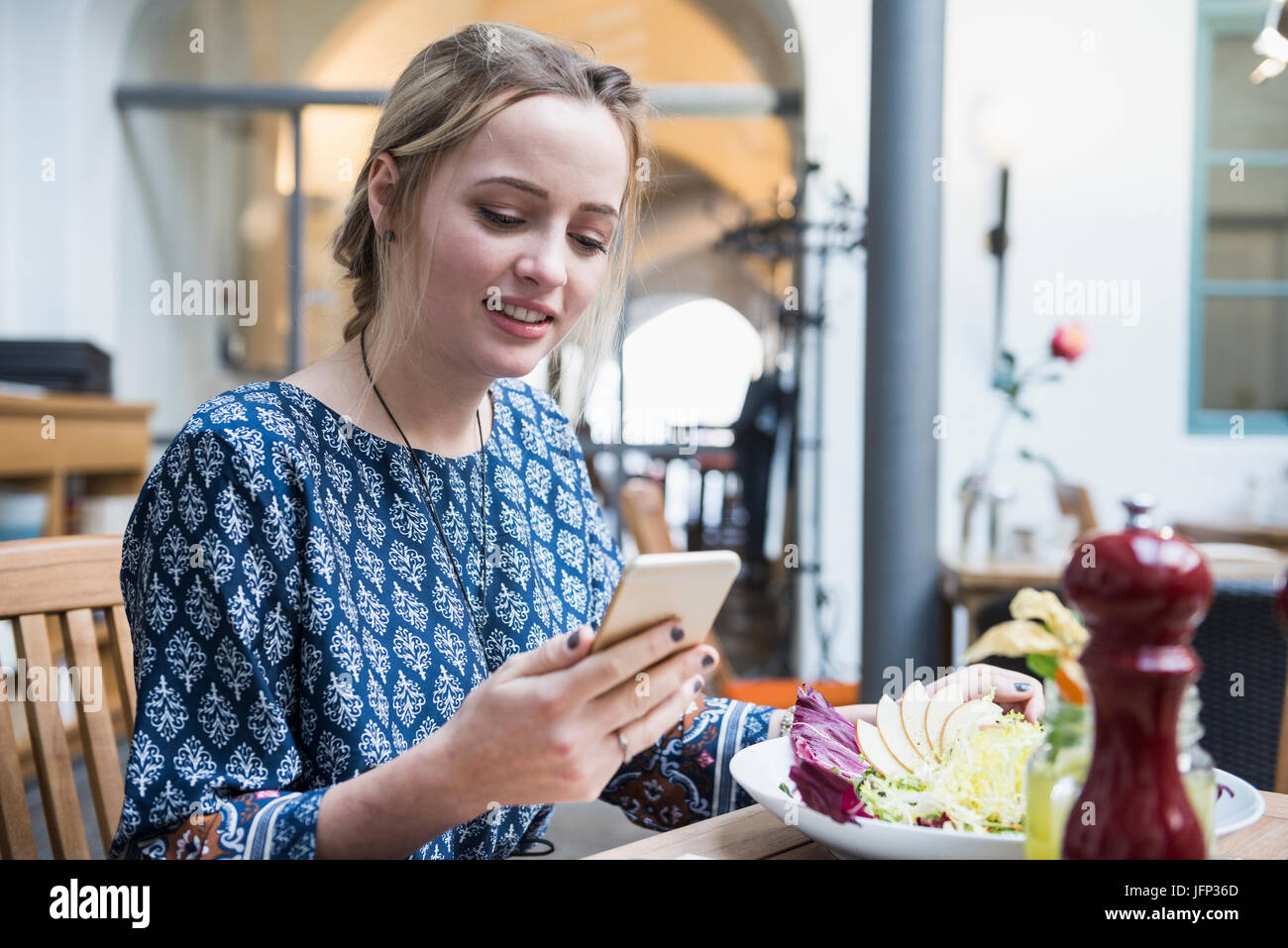 Junge Frau mit Handy beim Sitzen im restaurant Stockfoto