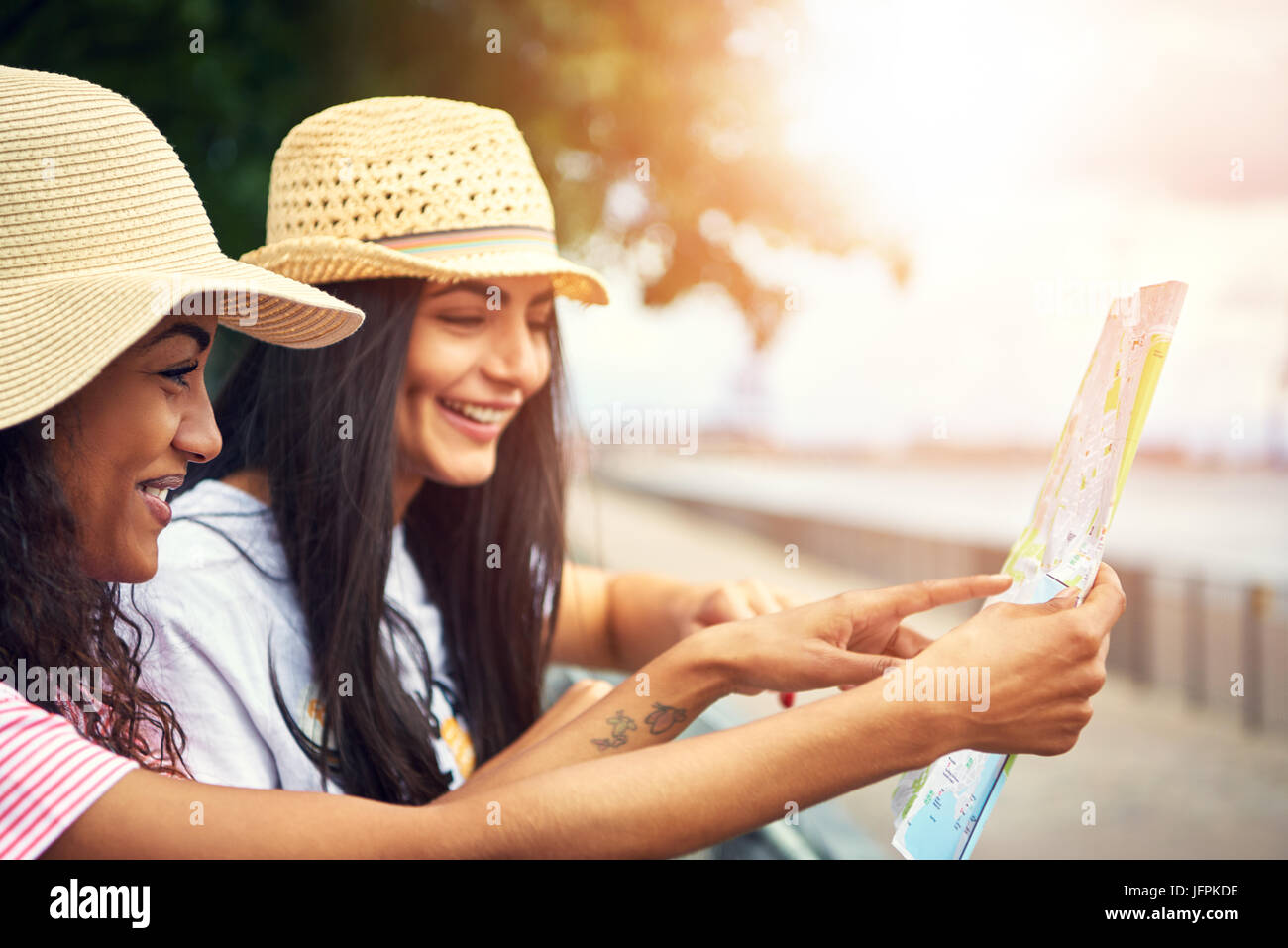 Paar nette weibliche Freunde bei Map im Freien in der Nähe der Waterfront Wanderweg mit Bäumen im Hintergrund Stockfoto