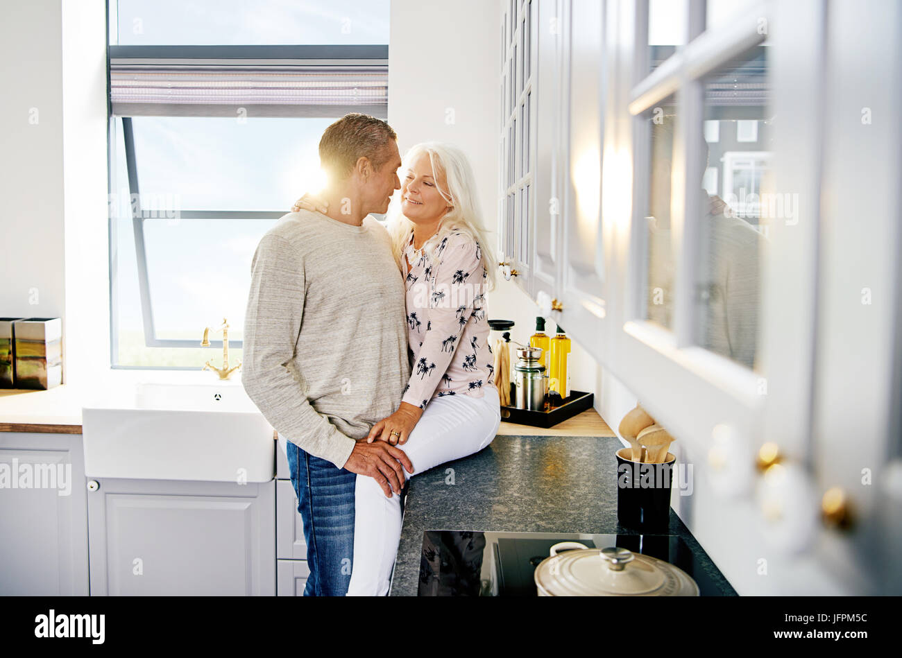 Herzlichen senior Paar lächelnd und in einem romantischen Moment zusammen, während Sie sich in Ihrer Küche zu Hause. Stockfoto