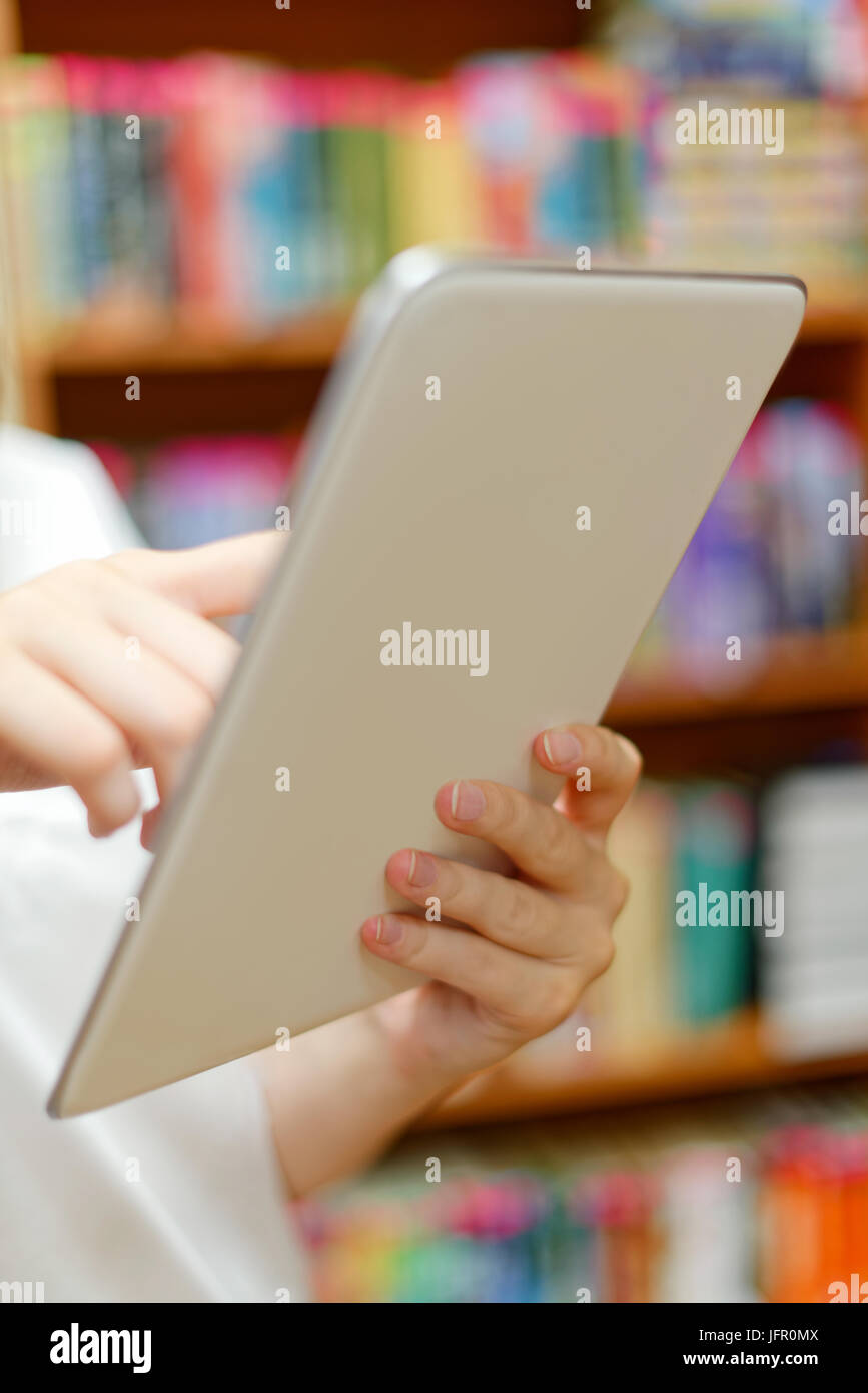 Personen: junges Mädchen, Studentin, die Nutzung der Tablet-Computer oder e-Book-Reader, in einer Bibliothek oder im Buchhandel Stockfoto