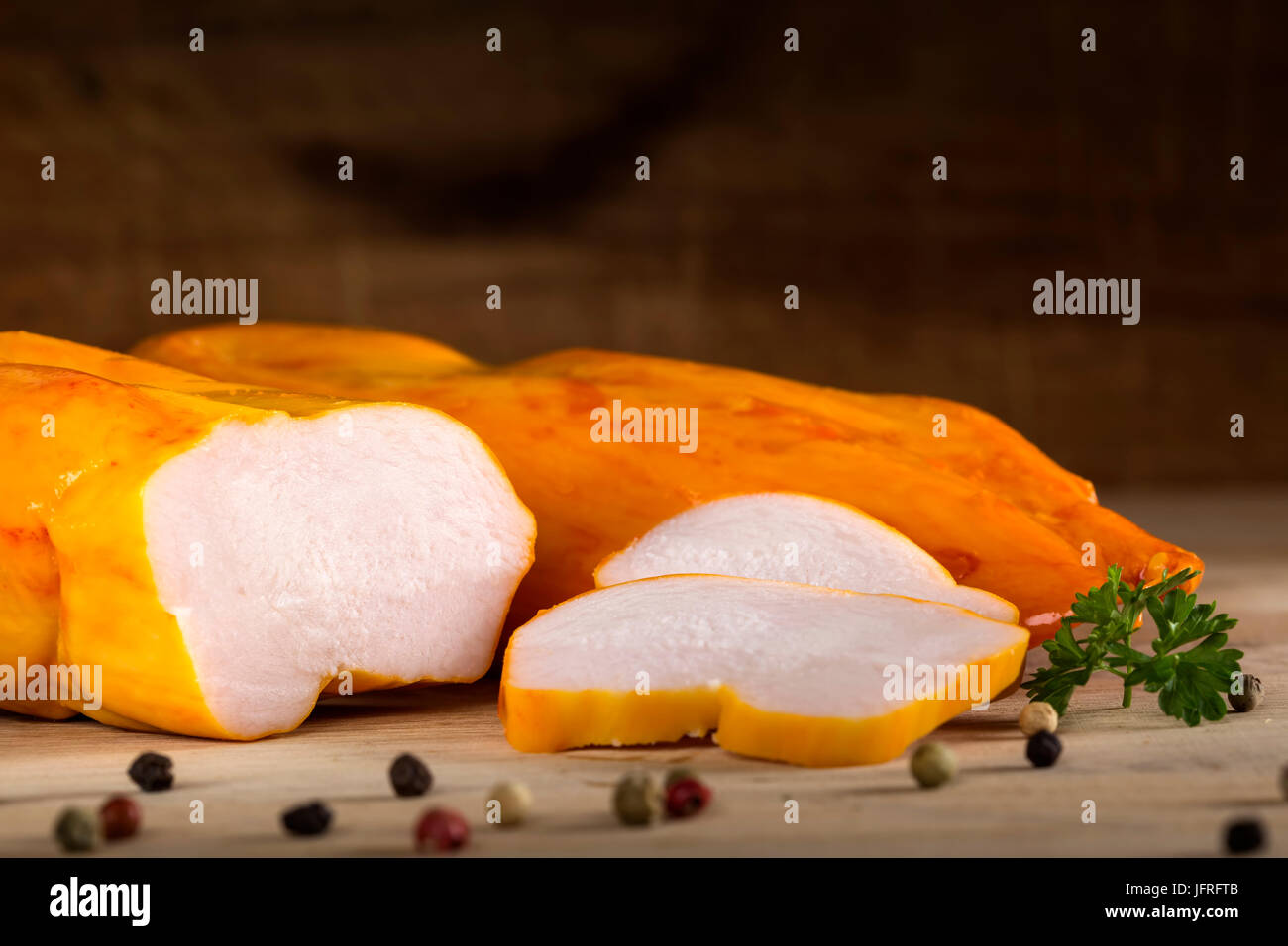 Nahaufnahme von Huhn Pastrami mit Pfeffer und Petersilie auf hölzernen rustikalen Hintergrund Stockfoto