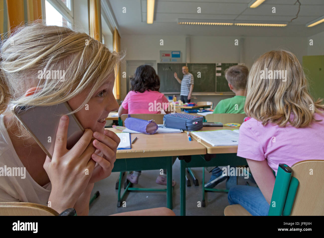 Grundschule Mädchen über ihr Mobiltelefon während des Unterrichts Stockfoto
