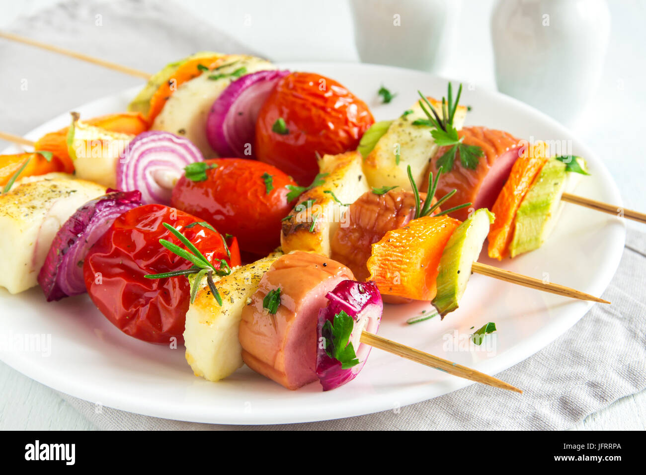 Grillwurst, Halluomi Käse und Gemüse Spieße mit frischen Kräutern auf weißen Teller Stockfoto