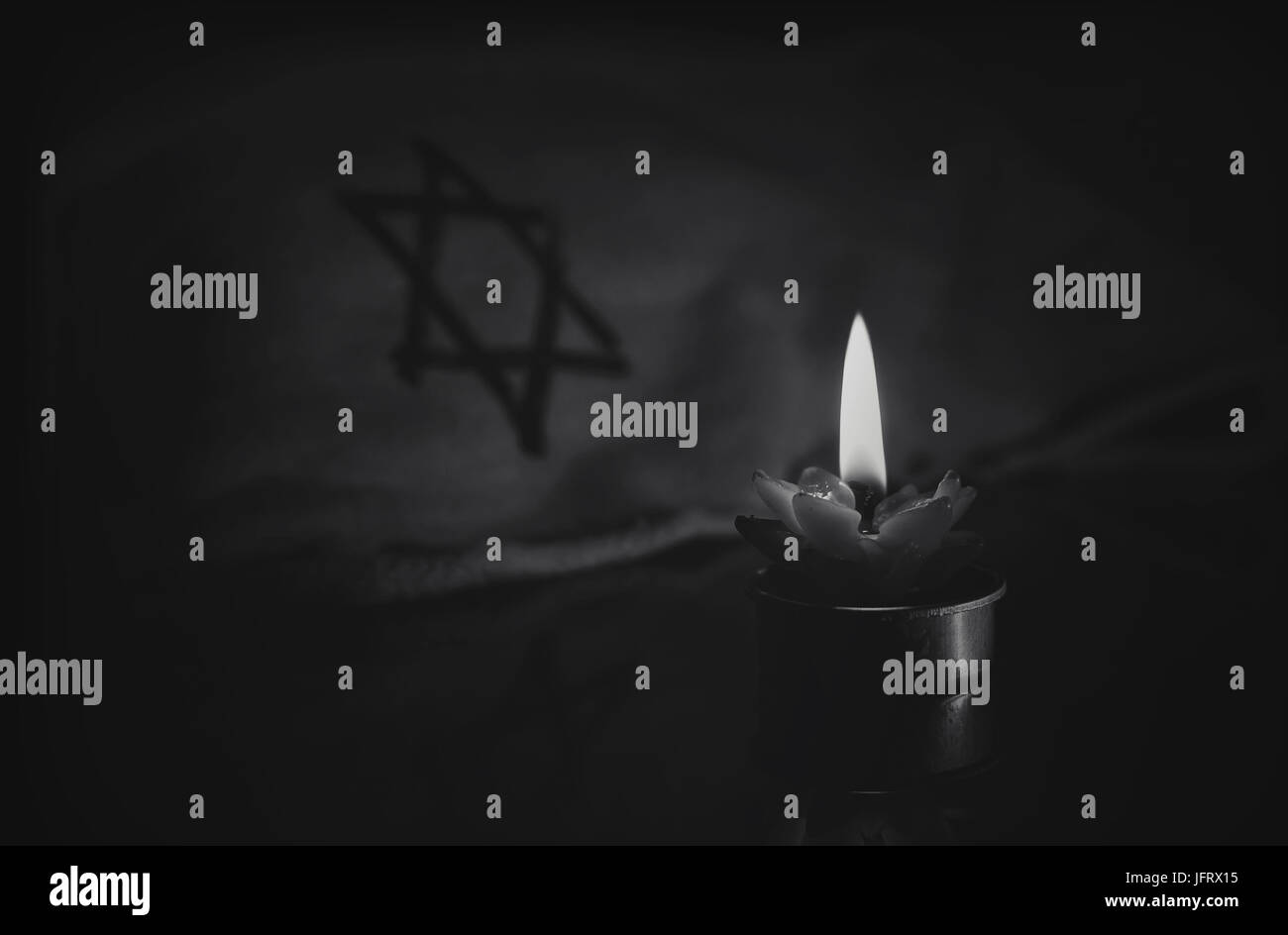 Eine brennende Kerze neben dem Davidstern auf einem schwarzen Hintergrund. Ein Symbol des Gedenkens an die Opfer des Völkermords an den Juden im dritten Reich Stockfoto