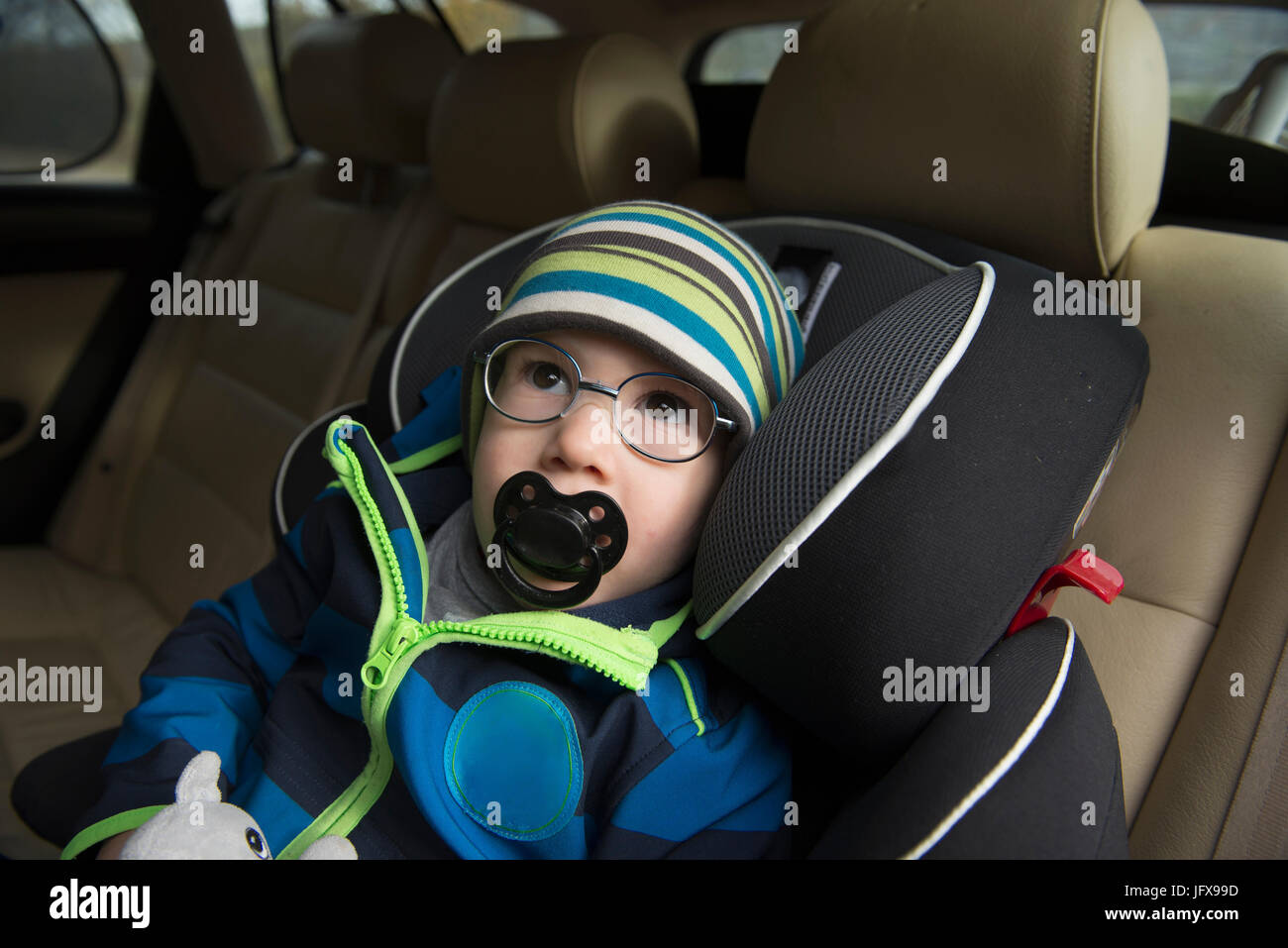 Kleiner Junge mit Schnuller im Mund sitzen im Autositz Stockfoto